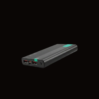 A black portable power bank with multiple USB-C ports, held by a black gloved hand in front of a display of its retail packaging boxes.